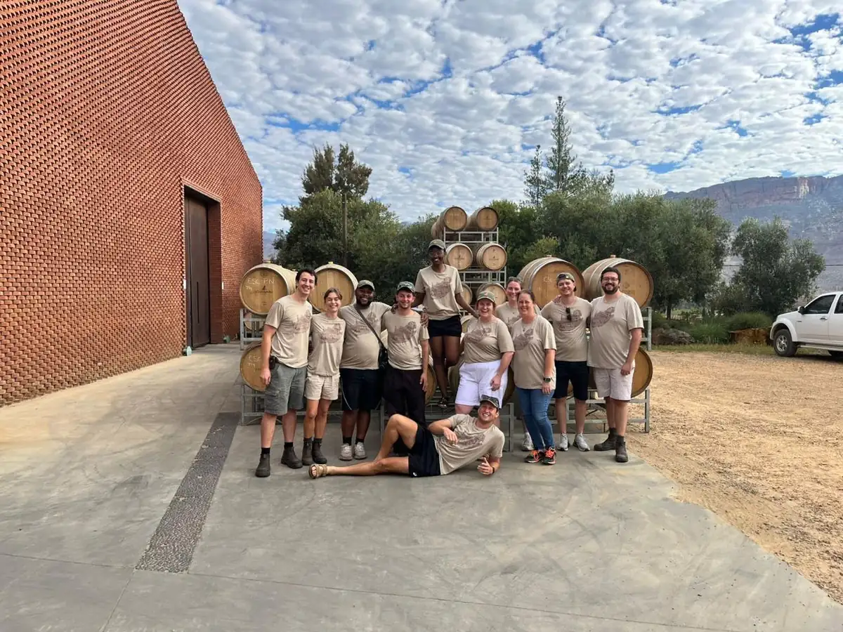 The group in matching shirts outside a brick winery with barrels behind them