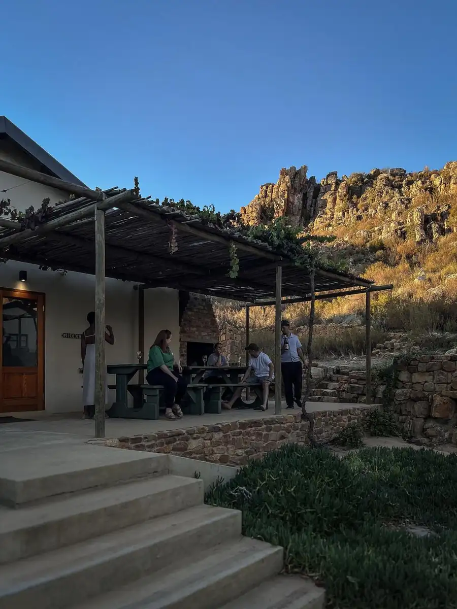 Sundowners under a reed and vine pergola at a cottage below the cliffs